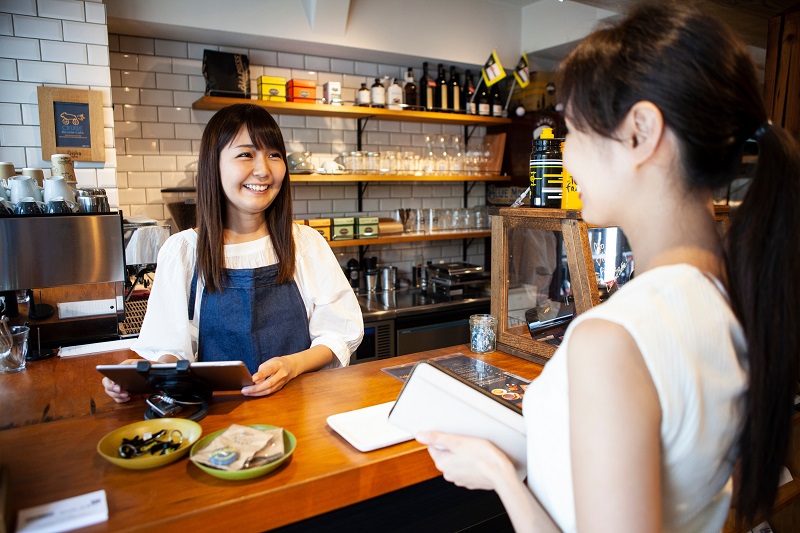 笑顔のカフェ店員とお会計をしようとする女性